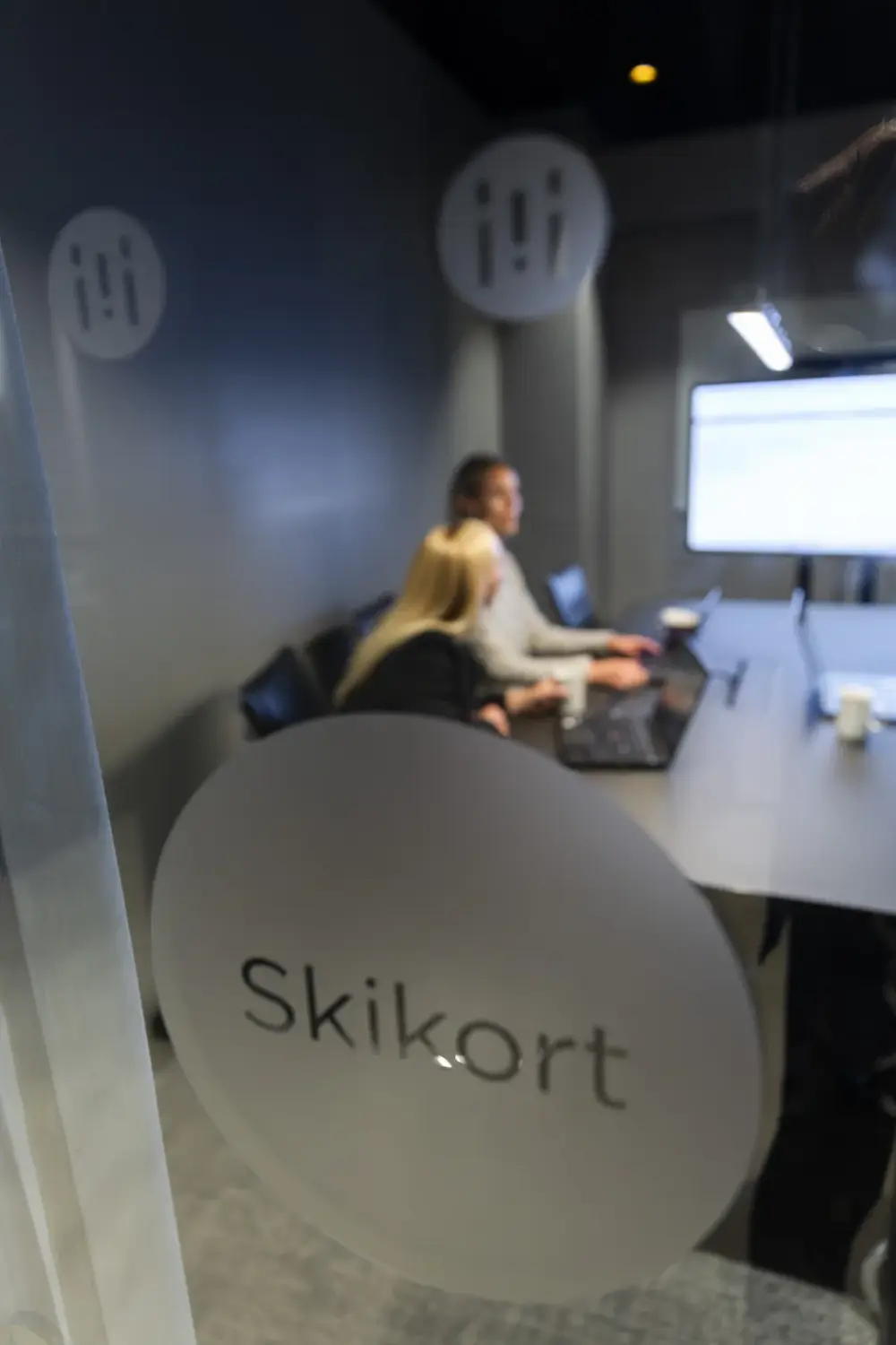 Microlog employees working in the ski pass meeting room, seen through the glass door.